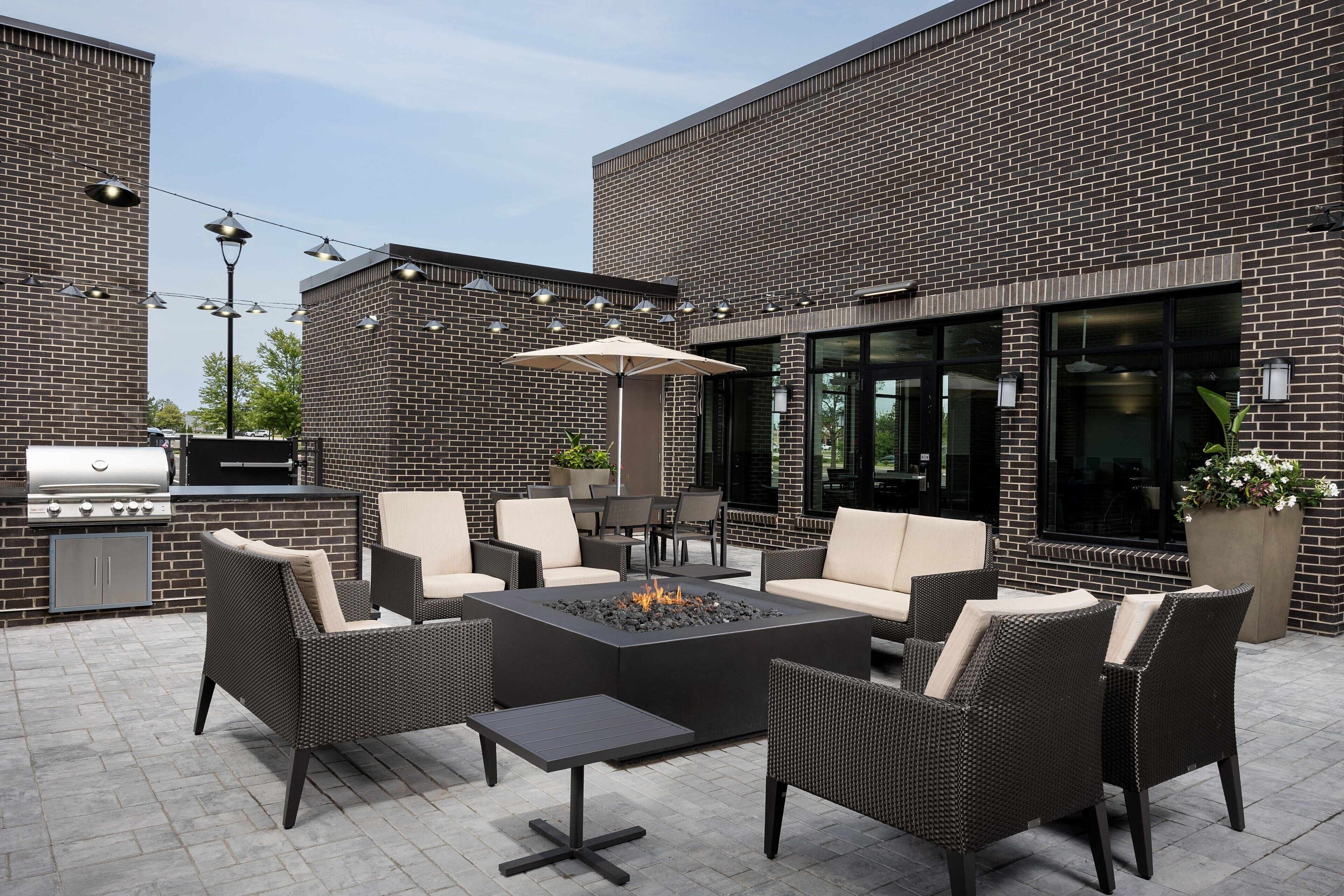 Un patio al aire libre con mobiliario de mimbre, una chimenea y una parrilla.