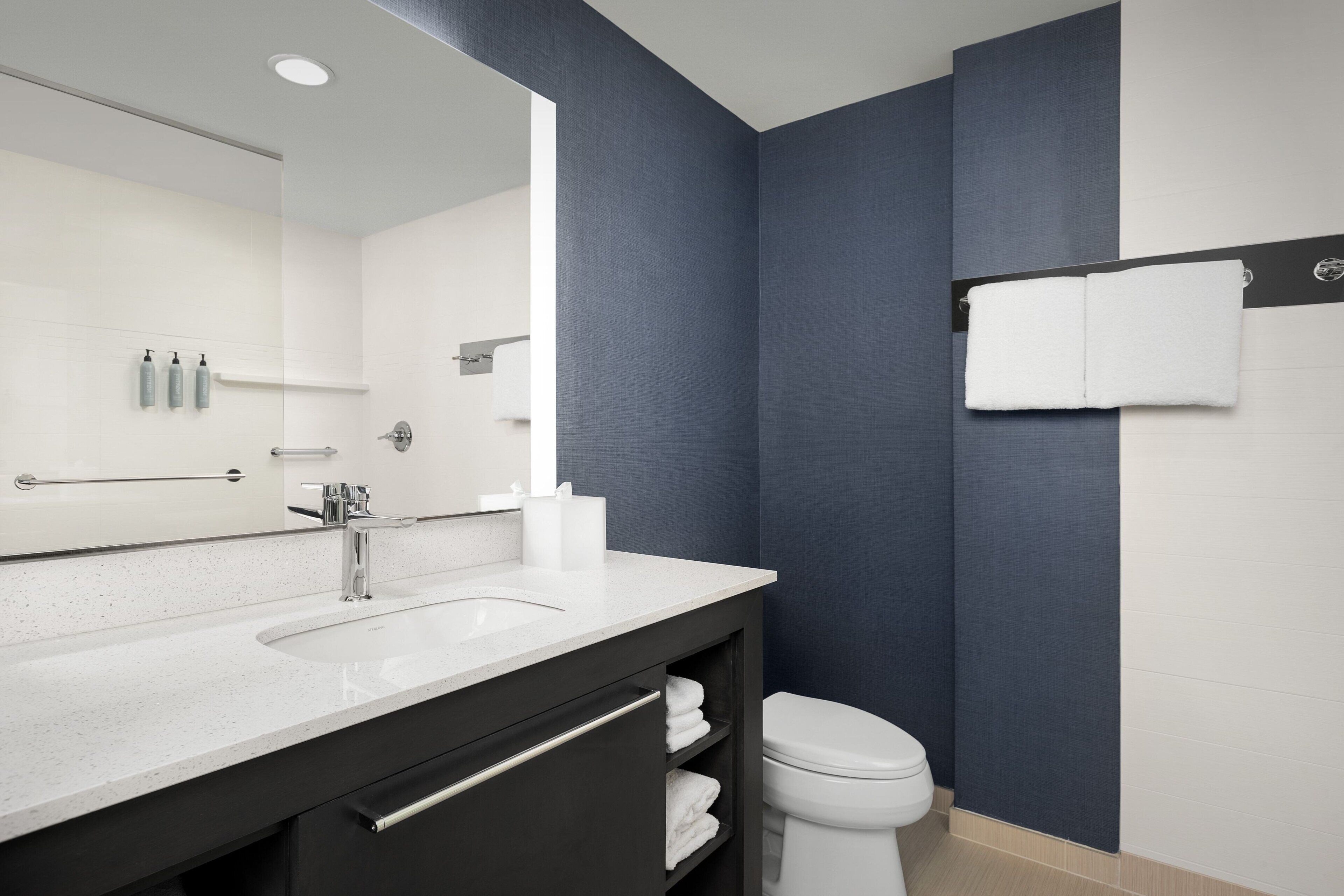 A modern bathroom with a dual-tone wall design, a large mirror, a white sink, and a toilet.