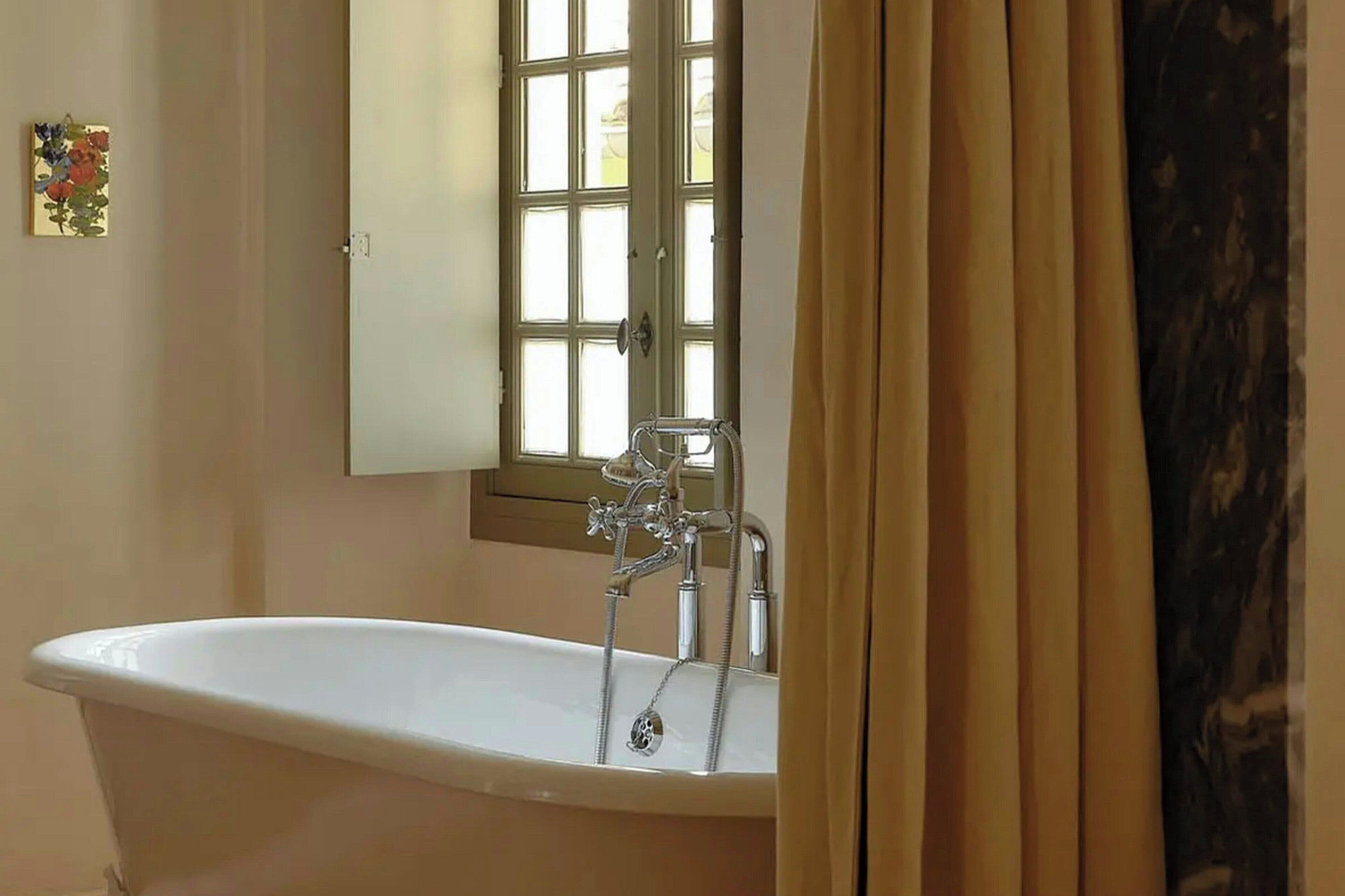 Une salle de bain avec une baignoire sur pieds, une fenêtre avec vue et une porte.