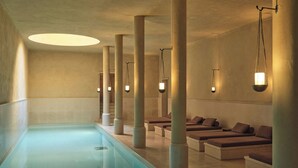 Spa-alue, jossa on pitkä uima-allas, pehmustetut istuimet ja riippuvalaisimet.
