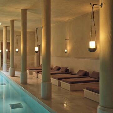 A spa area with a long pool, cushioned seating, and pendant lighting.