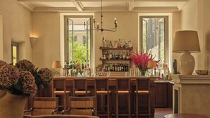 A bar area with wooden chairs, a bar counter with bottles, and a chandelier.