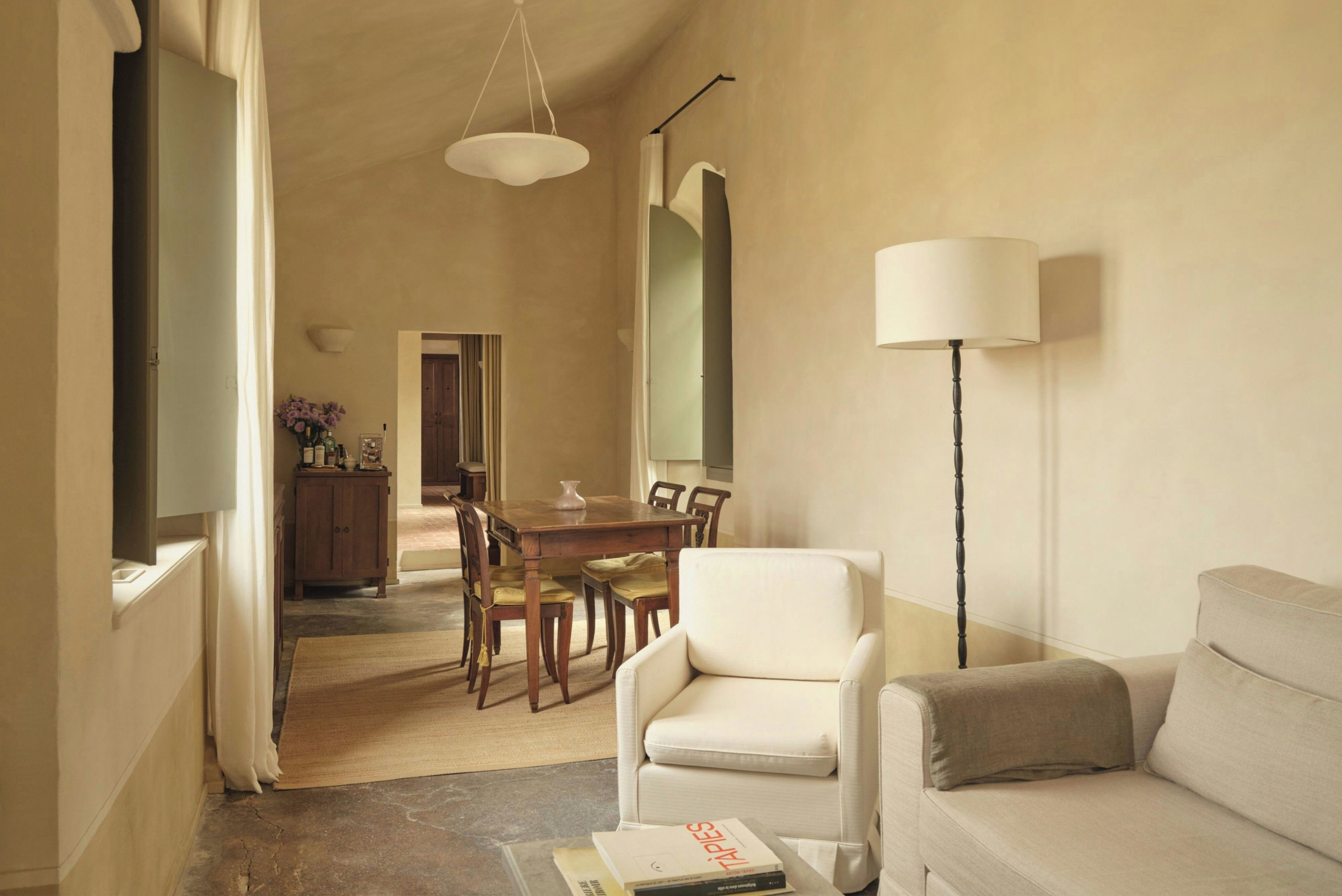 A living room with a sofa, a chair, a dining table with chairs, a lamp, and a television.
