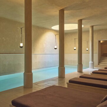 A spa area with a pool, benches, and columns.