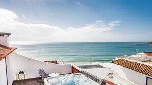 A rooftop terrace with a hot tub, a chair, and a view of the sea.