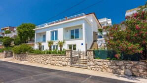 A modern two-story house with a stone wall, large windows, and a balcony. - Holiday apartment with air conditioning (Dramalj)