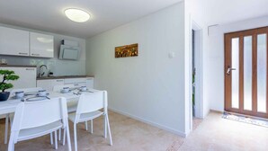 A modern kitchen with white cabinets, a dining table with chairs, and a potted plant. - Holiday apartment with air conditioning (Dramalj)