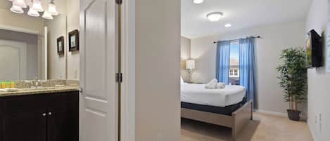 Une chambre d’hôtel avec une salle de bain, un lit, une télévision et une plante en pot.