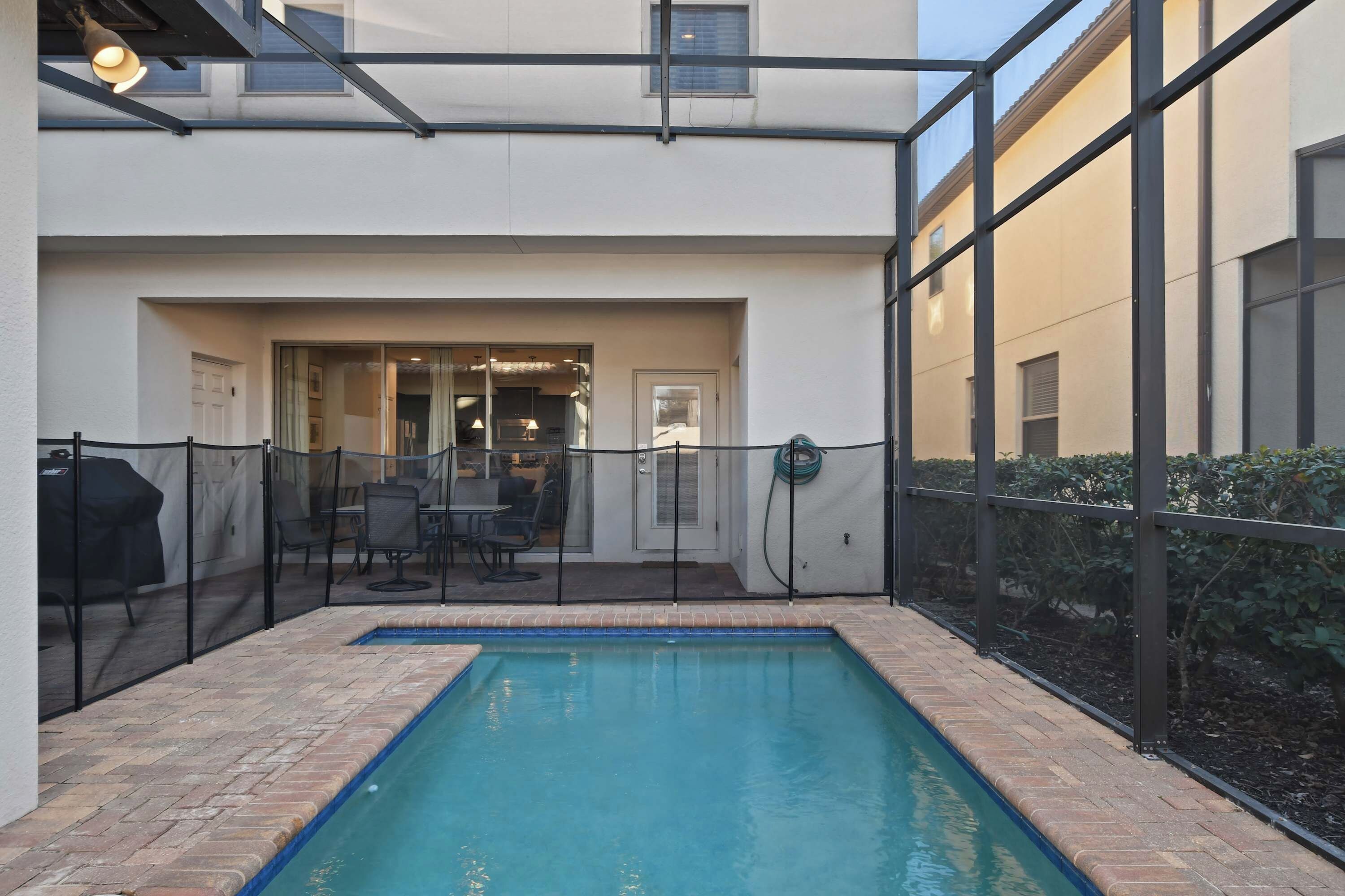 A pool area with a fenced patio, a covered outdoor seating area, and a view of the building's interior.