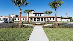 A two-story house with a tiled roof, surrounded by palm trees and a well-maintained lawn.