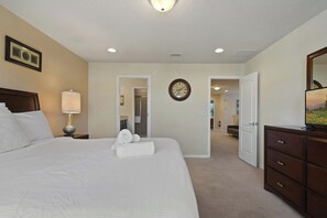 Een hotelkamer met een groot bed, een bedlamp, een klok, een spiegel en een dressoir.