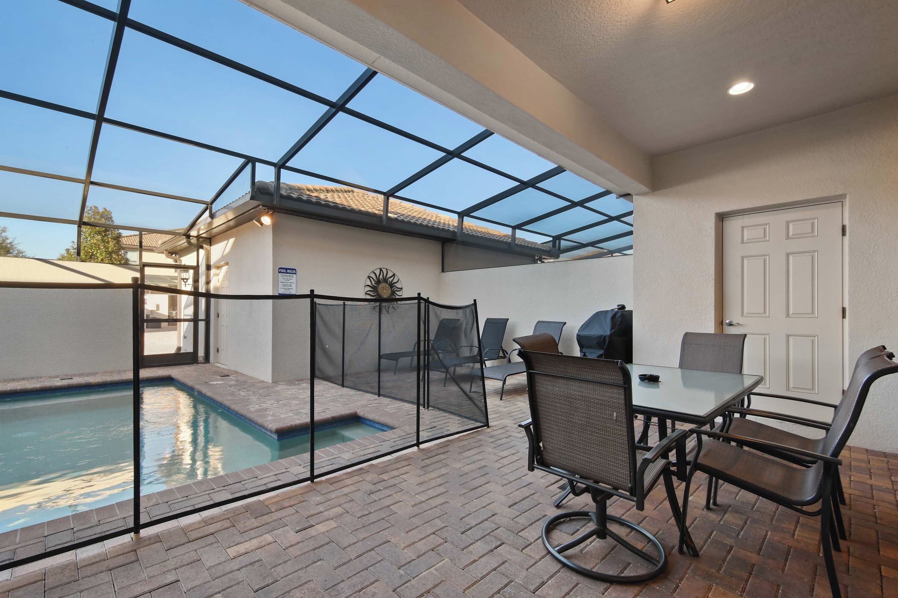 A covered outdoor area with a pool, seating, and a door.