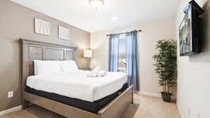Relax in a spacious room with a large bed, flat-screen TV, and a potted plant.