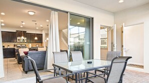Enjoy meals in the dining area with a glass-top table and metal chairs, and access to an outdoor space through a sliding glass door.