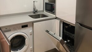 Une cuisine compacte équipée d’un lave-linge, d’un four à micro-ondes et d’un réfrigérateur.