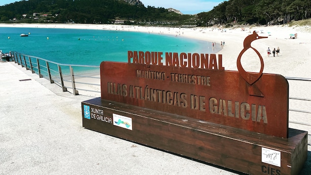 Un panneau de signalisation sur la plage portant les inscriptions « PARQUE NACIONAL MARÍTIMO-TERRESTRE ILLAS ATLÁNTICAS DE GALICIA » et « XUNTA DE GALICIA ».