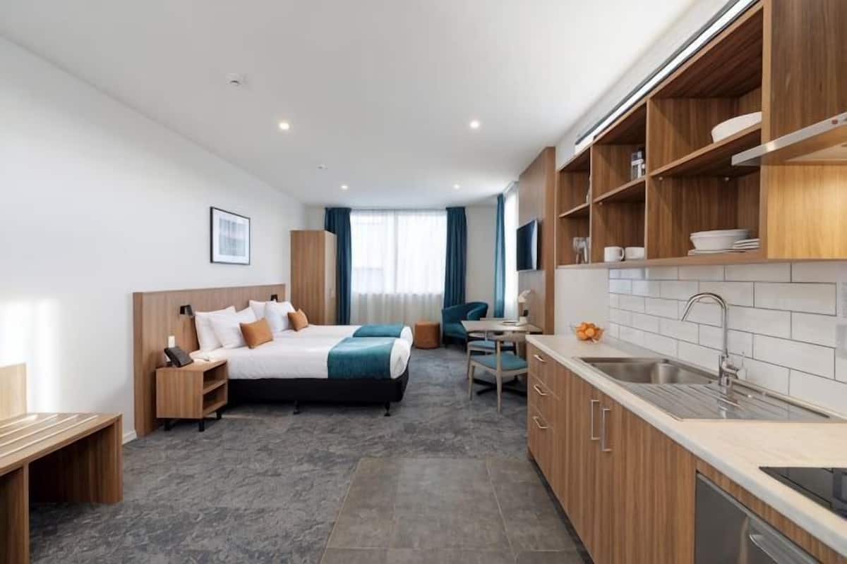 Une chambre d’hôtel moderne équipée d’un lit, d’un bureau et d’une kitchenette.