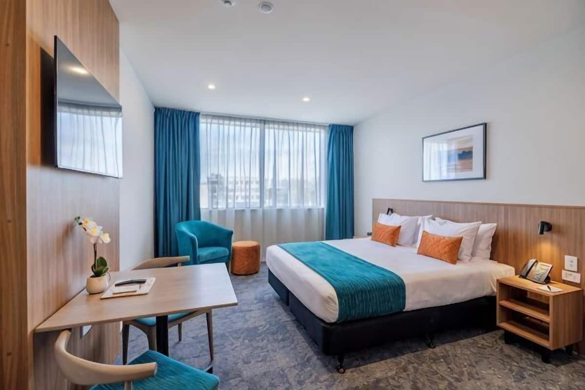 Une chambre d’hôtel équipée d’un lit, d’un bureau, d’une chaise et d’un téléviseur.