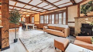 A cozy living room with a wooden ceiling, a fireplace, and a large window with shutters. - Luxury Cabin*Gym*Game Room*Fireplace (Lehighton)