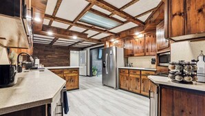 A spacious kitchen with wooden cabinets, a stainless steel refrigerator, and a granite countertop. - Luxury Cabin*Gym*Game Room*Fireplace (Lehighton)