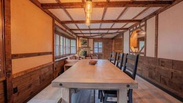 Una larga mesa de comedor con bancos, paredes de madera y una lámpara colgante en un interior acogedor.