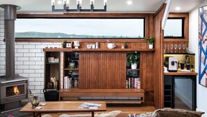 A modern living room with a fireplace, wooden shelves, and a coffee machine. - Marnies - Loft style country living (Shepherds Flat)