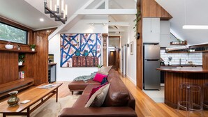A modern kitchen with a built-in refrigerator, wooden cabinets, and a bar area with stools. - Marnies - Loft style country living (Shepherds Flat)