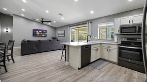 Una cocina moderna con una isla central, electrodomésticos integrados y una zona de comedor con sofá y sillas.