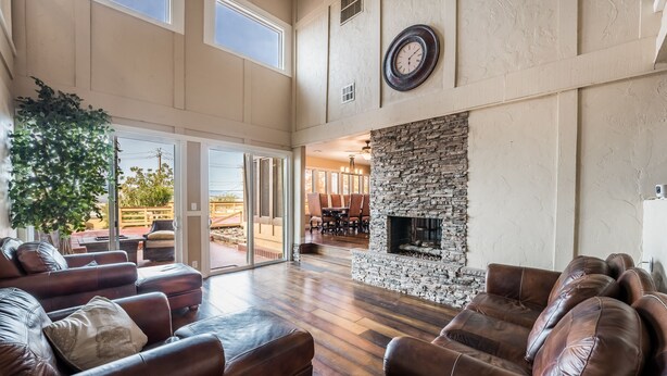 A spacious living area with leather sofas, a stone fireplace, and large windows. - Just in time for SUPER BOWL! Mansion with Luscious Strip Views! (Las Vegas)