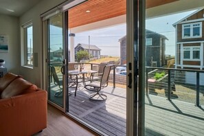 Una sala de estar moderna con un ventanal corredizo que da a una terraza de madera.
