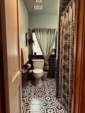 Casa de banho com sanita, lavatório e azulejos estampados.