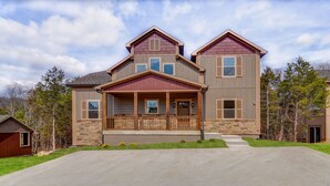 Une maison à deux étages avec une façade en pierre, un porche à l’avant et une allée.