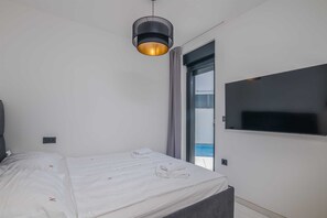 Et moderne hotelværelse med en seng, et fjernsyn monteret på væggen og et vindue med havudsigt.