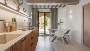 A modern kitchen with wooden cabinets, a built-in stove, and a dining area with a table and chairs. - Beautiful apartment with pool, WIFI, A/C, TV, veranda and panoramic view, close to San Gimignano (Montaione)