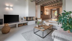 A modern living room with a flat-screen TV, a wooden coffee table, and a sofa. - Beautiful apartment with pool, WIFI, A/C, TV, veranda and panoramic view, close to San Gimignano (Montaione)