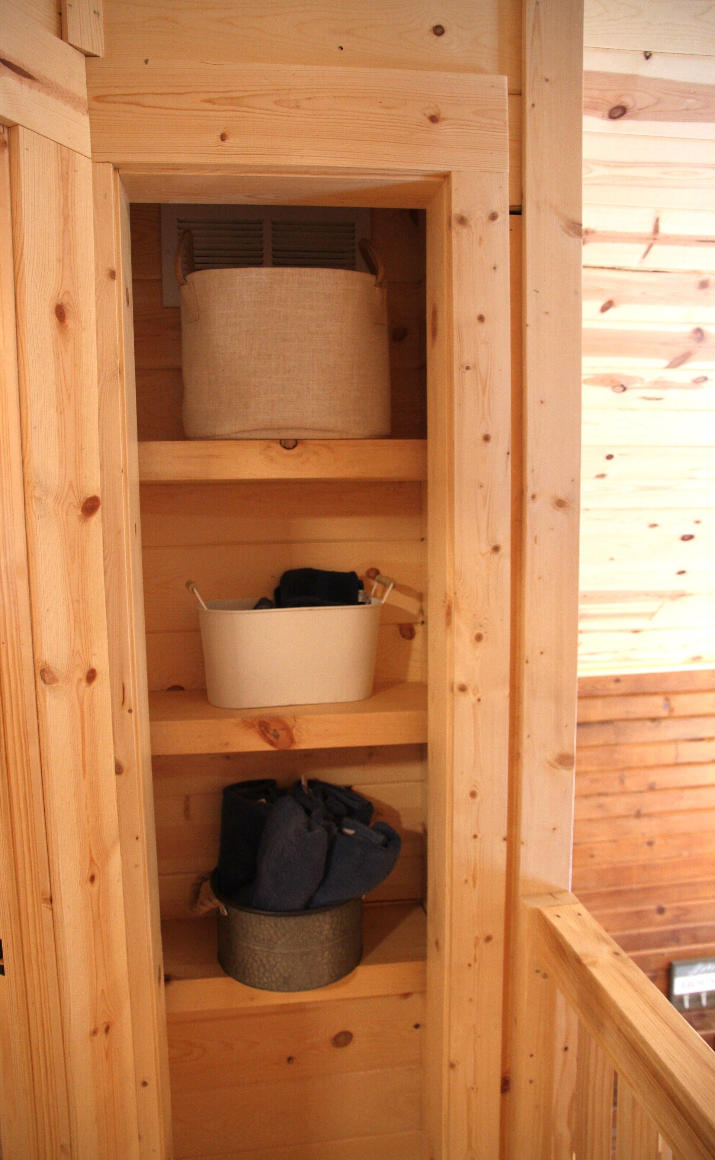 A wooden interior with a built-in shelf unit containing storage bins and a hanging garment.