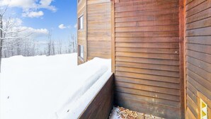 Uma cabana de madeira com o chão coberto de neve e um céu limpo.
