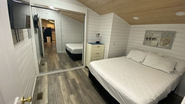 Un dormitorio con cama, mesita de noche y espejo.