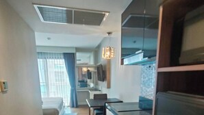 Una habitación de hotel compacta con kitchenette, comedor y cama.
