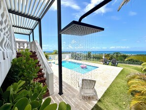 A pool area with a view of the ocean, a covered patio with stairs, and outdoor seating. - Endless ocean views and pool, by El Yunque. (Río Grande)