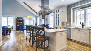 A spacious kitchen with a central island, white cabinetry, and a large window providing natural light. - Blue Skies - Lakefront Living at it's Finest! Luxury Amenities! (Honeoye)