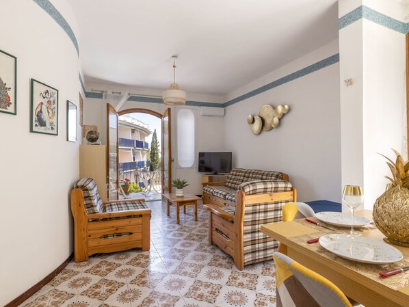 Una habitación acogedora con una cama, una silla de madera, una mesa de comedor con platos y una copa de vino, y un televisor.