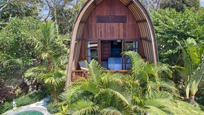 Una cabaña de madera con balcón, rodeada de exuberante vegetación tropical.