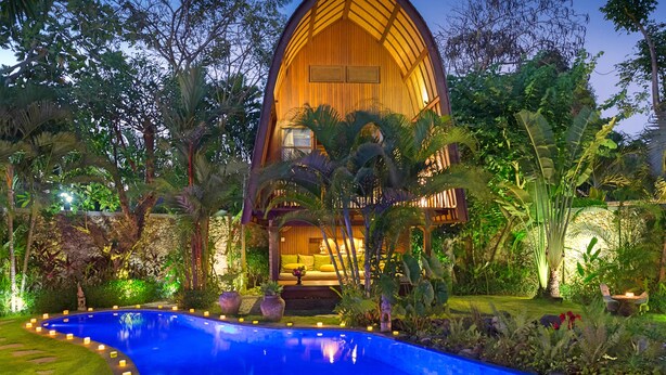 Una estructura grande con forma de A, hecha de madera, con una piscina al frente.