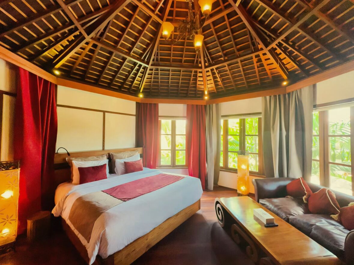 A spacious room with a large bed, a wooden table, and a sofa.
