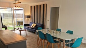Un salon moderne comprenant un canapé, une table à manger avec des chaises et un coin cuisine.