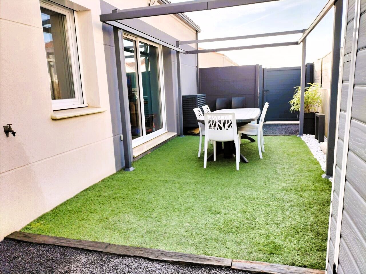 A patio area with a table and chairs, a small grassy patch, and a sliding glass door.