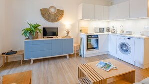 A modern kitchen with white cabinets, a built-in oven, microwave, and washing machine.