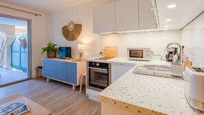 A modern kitchen with white cabinetry, a microwave, a stove, and a coffee maker.