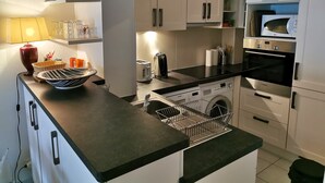 A compact kitchen with a washing machine, microwave, oven, and a sink. - The Dunes of Blossac 100m from the beach (Les Sables-d´Olonne)
